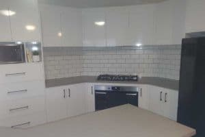 White kitchen with subway tiled splashback behind the cooktop