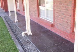 Outdoor tiled patio and paving alongside a brick home, an external floor tiling job