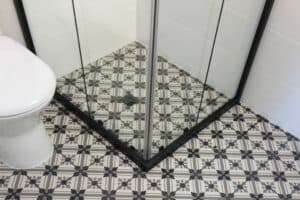 Close up of a patterned black and white tiled shower base against a frameless glass screen